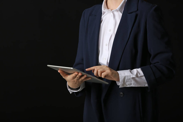 Businesswoman with tablet computer on dark background - Foto, afbeelding