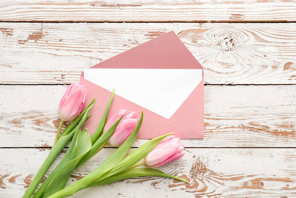 Envelope with card and flowers on white wooden background - Foto, Imagem