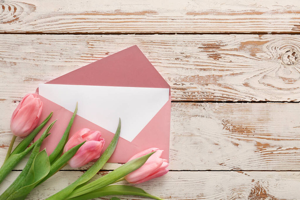 Envelope with card and flowers on white wooden background - Foto, imagen
