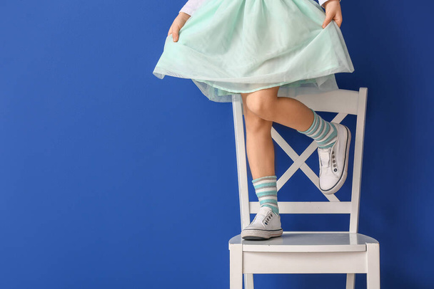 Klein meisje staand op stoel tegen kleur achtergrond - Foto, afbeelding