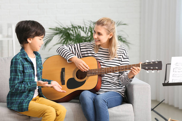 Privé muziek leraar geven gitaar lessen aan kleine jongen thuis - Foto, afbeelding