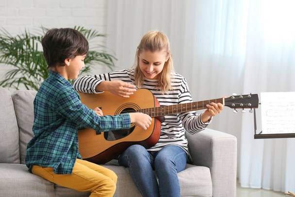 Profesora de música privada dando clases de guitarra a un niño en casa
 - Foto, imagen