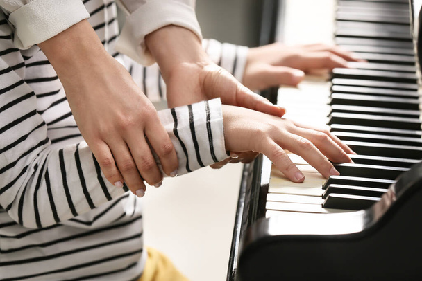 Приватний вчитель музики дає уроки фортепіано маленькому хлопчику, крупним планом
 - Фото, зображення