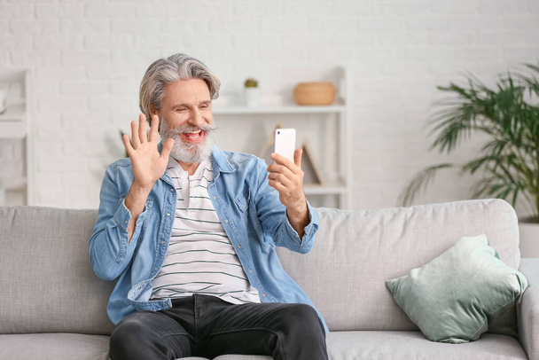 Boldog idős férfi mobiltelefonnal otthon - Fotó, kép