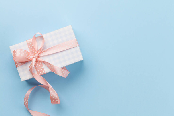 Grußkarte mit pastellfarbenem Geschenkkarton auf blauem Hintergrund. Draufsicht flach liegend mit Platz für Ihre Grüße - Foto, Bild