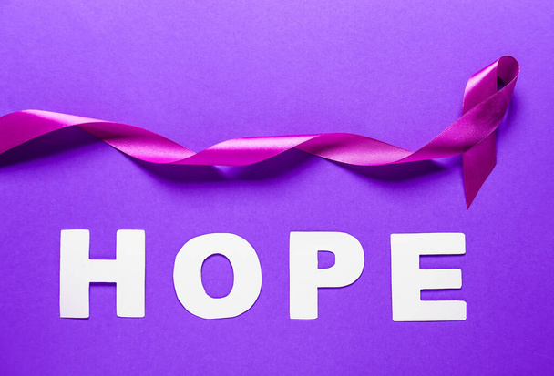 Fioletowa wstążka i słowo Nadzieja na tle koloru. Koncepcja przemocy domowej - Zdjęcie, obraz
