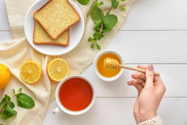 Woman drinking tea with honey at table, top view - Photo, Image