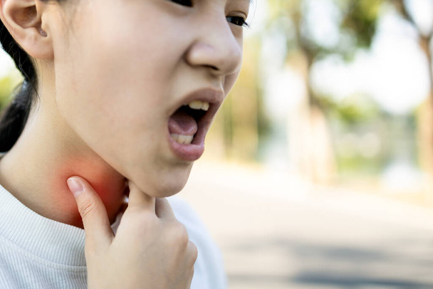 Doente menina asiática tem dor de garganta, tosse, rouquidão, câncer de laringe, mão tocar seu pescoço, mulher com problema de garganta, amigdalite, perda de voz, infecção da gripe, resfriados, vírus, bactérias na laringe
  - Foto, Imagem