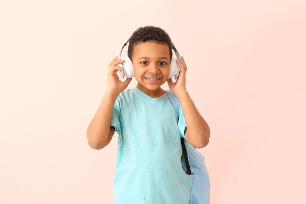 Милий афро-американський школяр з навушниками на кольоровому фоні - Фото, зображення