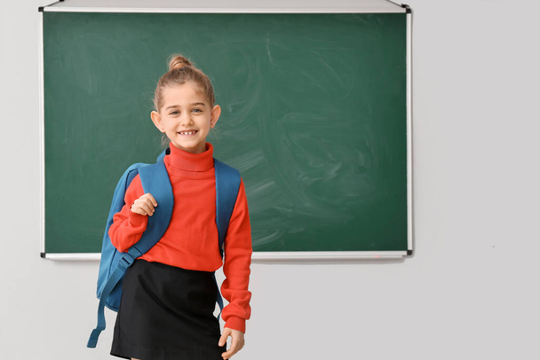 Cute little schoolgirl near blackboard in classroom - Fotó, kép