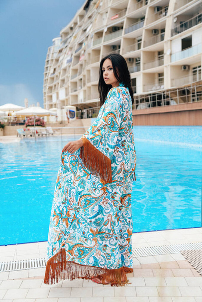 fashion outdoor photo of beautiful girl with dark hair in elegant swimming suit posing near swimming pool - Fotó, kép