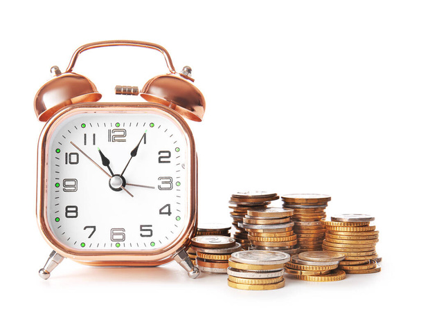 Relógio despertador e moedas em fundo branco. Conceito de gestão do tempo
 - Foto, Imagem