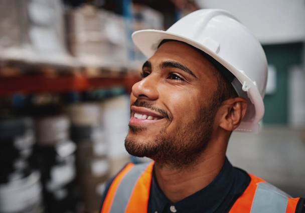 Close-up lateral do bem sucedido trabalhador afro-americano masculino olhando para longe no armazém vestindo um capacete branco
 - Foto, Imagem