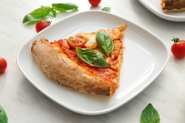 Talerz z kawałkiem pysznej pizzy Margherita na stole - Zdjęcie, obraz