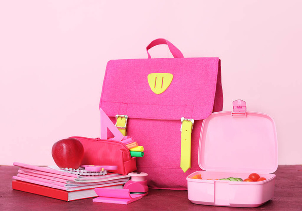 School backpack with lunch box and stationery on color background - Foto, Imagem