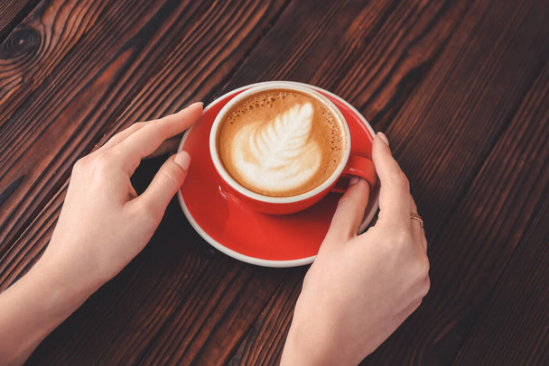 Frau trinkt leckeren Cappuccino am Holztisch - Foto, Bild