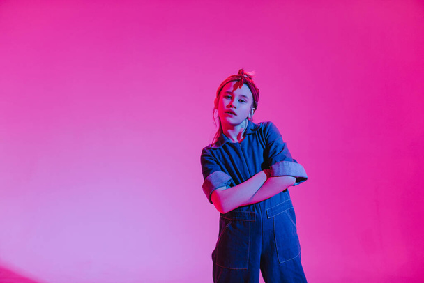 Mladá stylová dívka tančí v ateliéru na barevném neonovém pozadí. Design plakátu Music DJ. - Fotografie, Obrázek