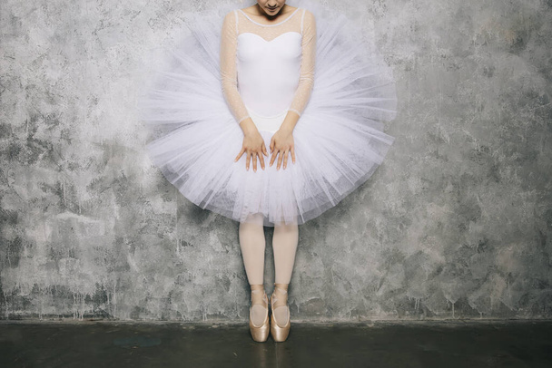 Pretty young ballerina dancer dancing classical ballet against rustic wall - Photo, Image