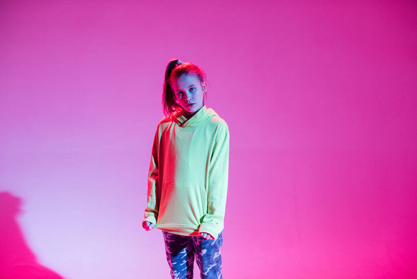 Nuori tyylikäs tyttö tanssii studiossa värillisellä neontaustalla. Musiikki dj juliste suunnittelu
. - Valokuva, kuva