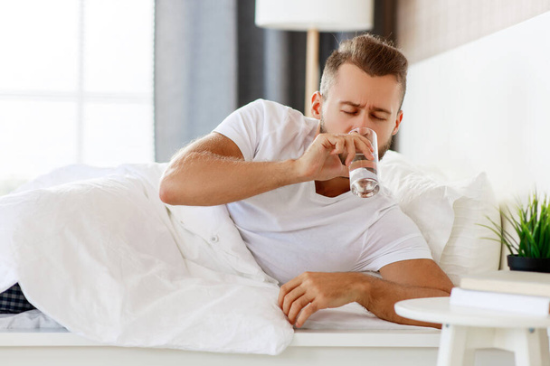 young healthy man drinking water in morning at window - Photo, image