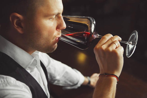 Sommelier tastes red wine by drinking beverage, man tasting alcoholic drink - Photo, image