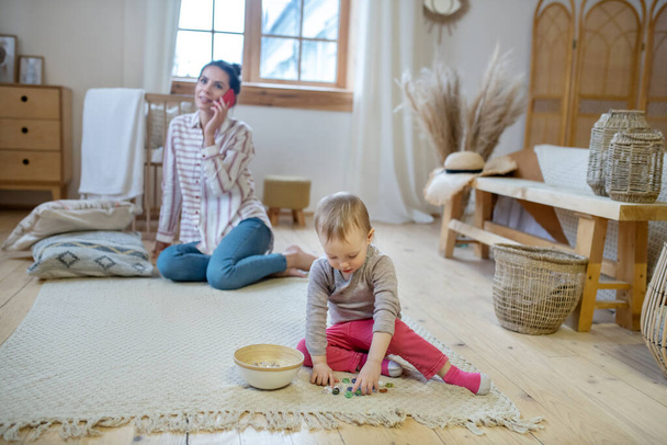 Daughter playing with artificial stones, mom talking on the phone - Foto, imagen