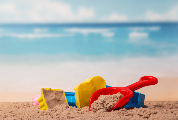 Bright children's toys in the sand against the sea. - Foto, afbeelding