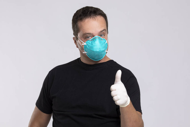 Man met een masker en chirurgische handschoenen geeft een duim omhoog. - Foto, afbeelding