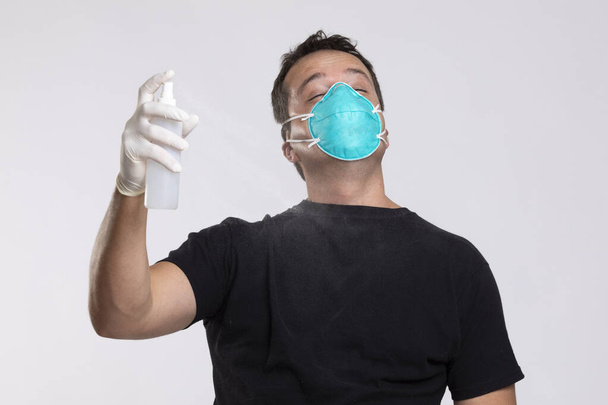 Homem na máscara desinfectando-se com spray higienizante
. - Foto, Imagem