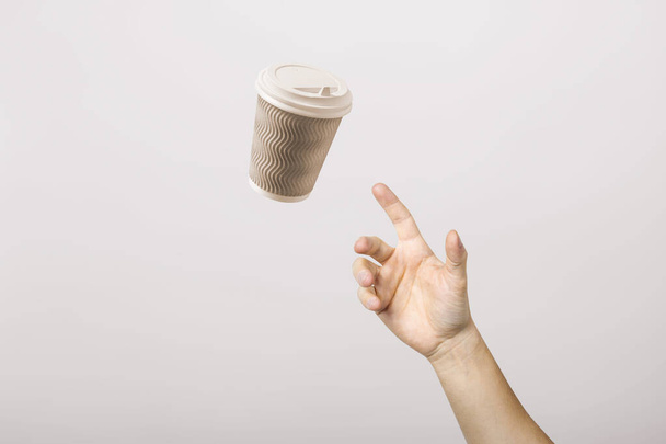 hand catches a cardboard glass on a light cardboard background. Concept of coffee, tea, advertising, coffee breaks. - Photo, image