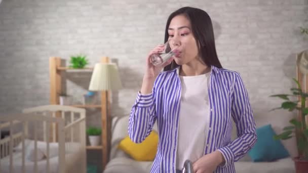 Positive young asian woman drinks clean fresh water - Materiał filmowy, wideo