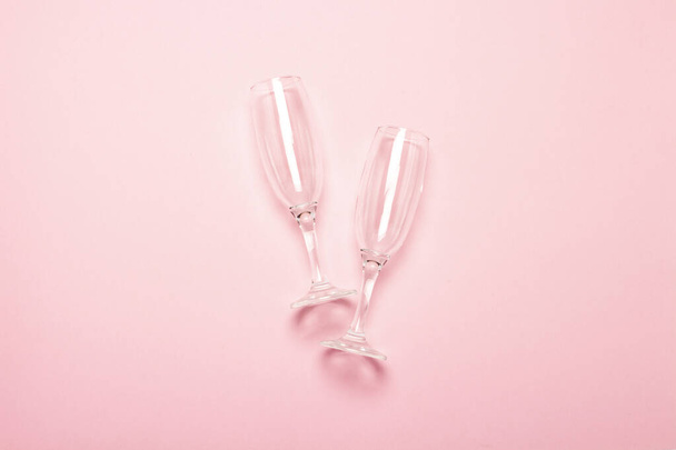 δύο άδεια ποτήρια σαμπάνιας σε ανοιχτό ροζ φόντο. Η ιδέα ενός γάμου, γενεθλίων, επετείου, πάρτι, μπάτσελορ πάρτι. Μπάνερ. - Φωτογραφία, εικόνα