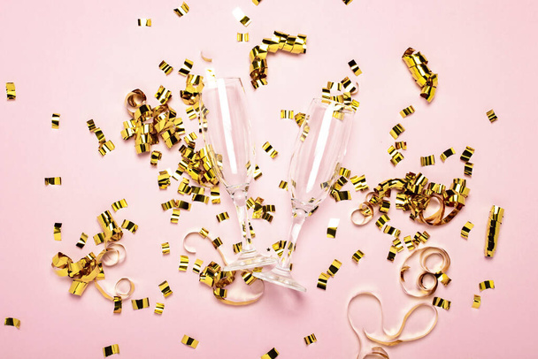 two empty champagne glasses and golden confetti scattered on a pale pink background. Wedding concept, birthday, anniversary, party, bachelorette party. Banner. - 写真・画像