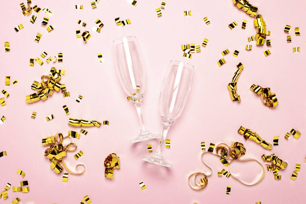 two empty champagne glasses and golden confetti scattered on a pale pink background. Wedding concept, birthday, anniversary, party, bachelorette party. Banner. - Photo, Image
