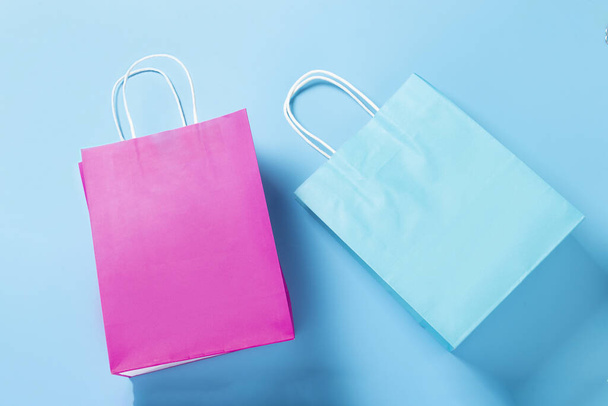 青い背景の青とピンクのパケットです。ショッピングパッケージ。休日、ショッピング、販売、割引の概念。バナーだ。トップビュー、フラットレイアウト. - 写真・画像