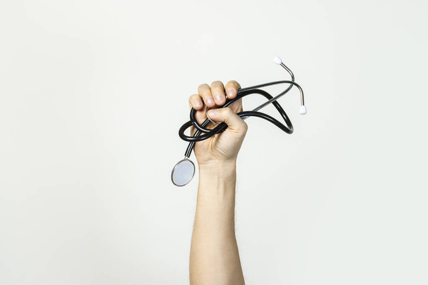 Männliche Hand hält ein Stethoskop auf einem leicht isolierten Hintergrund. Konzeptmedizin, Erste Hilfe, medizinische Ausbildung, Praktikum. Banner. - Foto, Bild