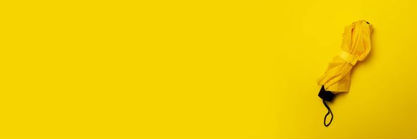 Guarda-chuva amarelo sobre um fundo amarelo isolado. O conceito de chuva, outono, proteção, elegante, na moda. Banner. Deitado plano, vista superior
. - Foto, Imagem