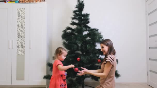 happy mother and little daughter decorating christmas tree at home. concept family, winter holidays and people. - Footage, Video