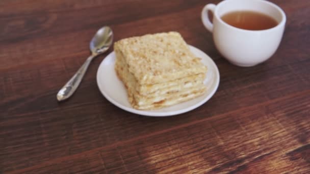 Κύπελλο του τσαγιού με κέικ σε καφέ φόντο τραπέζι - Πλάνα, βίντεο