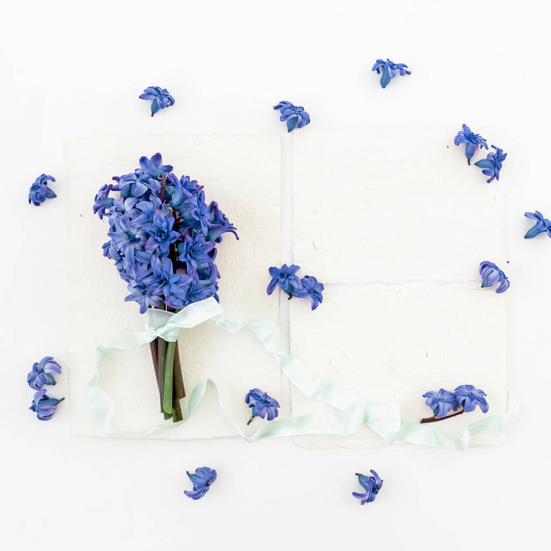 Ramo floral hecho de flores de jacinto, pétalos y cintas sobre fondo blanco. Piso tendido, vista superior
. - Foto, imagen