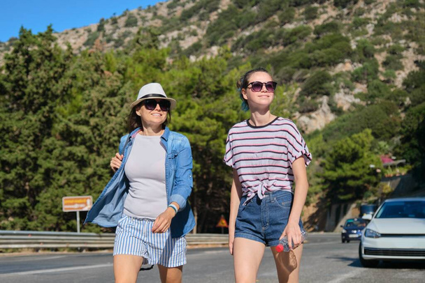 Two women walking on sunny summer day on mountain road - Foto, afbeelding