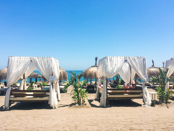 Sonnenliegen an der Sandstrandküste im Sommer, luxuriöses mediterranes Resort als Reise- und Urlaubsziel - Foto, Bild