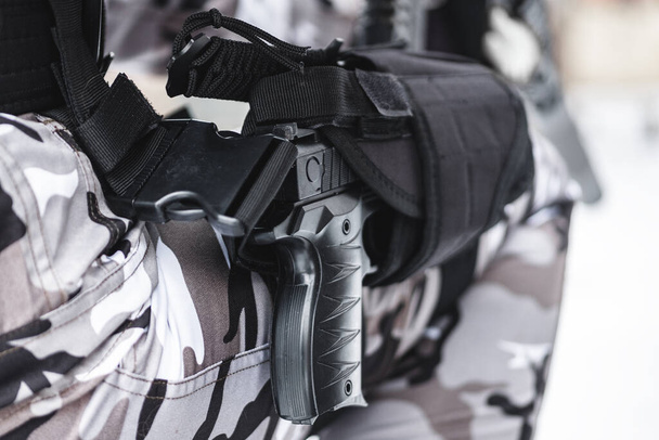 A pistol in a holster on a military foot. Close up. - Photo, image