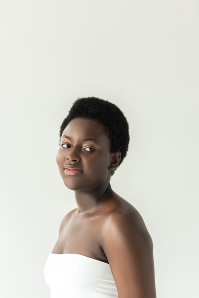 attractive smiling african american girl in white top isolated on grey - Fotó, kép