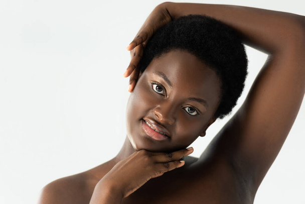 smiling naked african american girl touching face isolated on grey - Фото, зображення