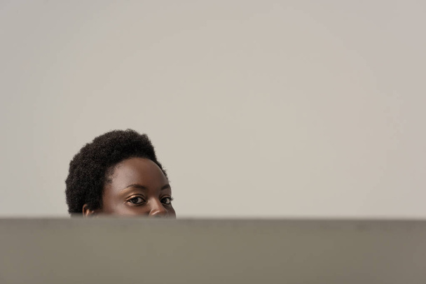 abgeschnittene Ansicht einer afrikanisch-amerikanischen Frau am Tisch isoliert auf grau - Foto, Bild