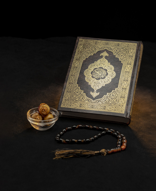 Ιερό Βιβλίο του Κορανίου με Ροζάριο και ημερομηνίες σε μαύρο φόντο, Γιορτάζοντας Ιερό Μήνα του Ραμαζανίου - Φωτογραφία, εικόνα