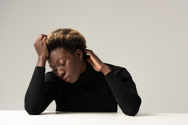 pensive african american woman in black turtleneck sitting at table isolated on grey - Fotografie, Obrázek