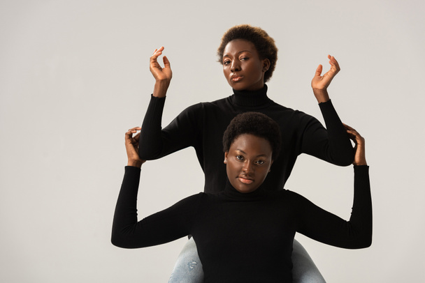 female african american friends in black turtlenecks gesturing isolated on grey - Photo, Image