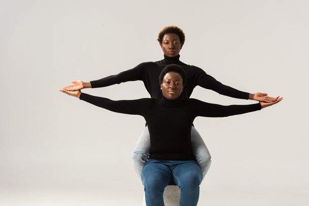 meninas americanas africanas em golas pretas tocando mãos isoladas em cinza
 - Foto, Imagem